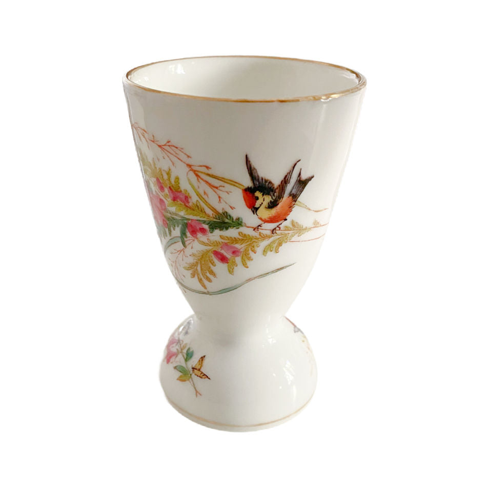 Antique French hand-painted footed egg cup with bird and butterflies , featuring delicate botanical detail and soft pastel pink floral branches.