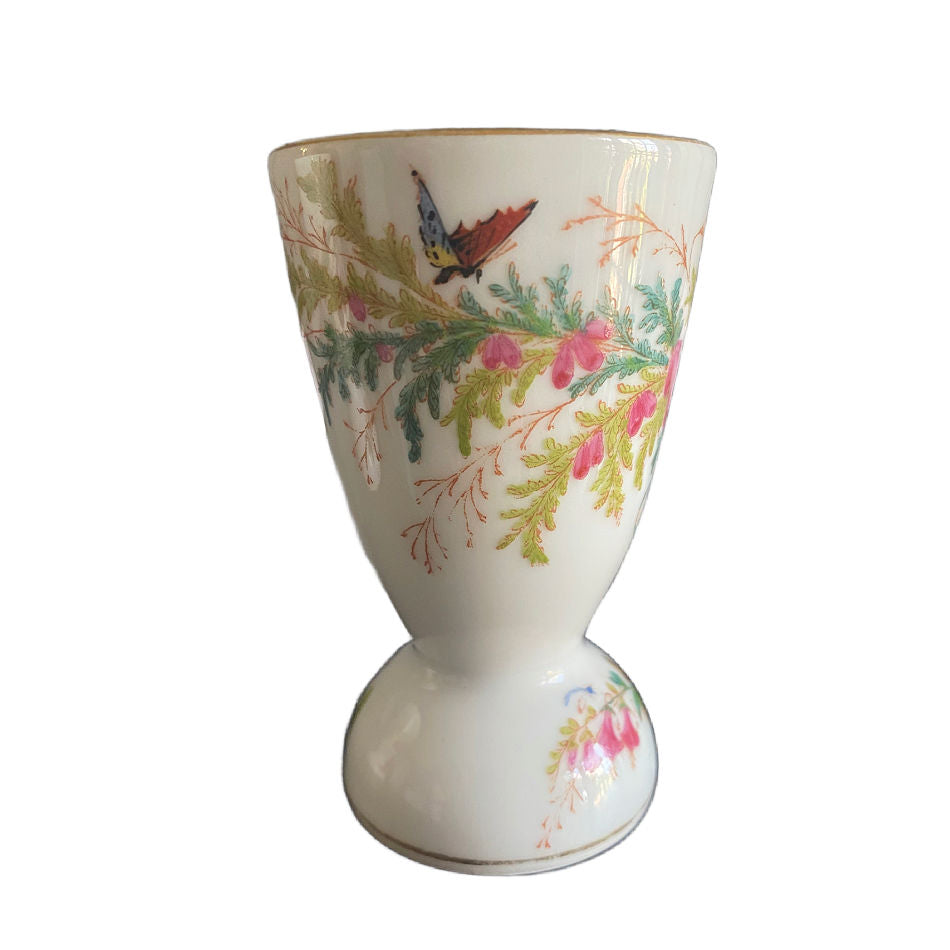 Antique French hand-painted footed egg cup with bird and butterflies, featuring delicate botanical detail and soft pastel colored pink florals.
