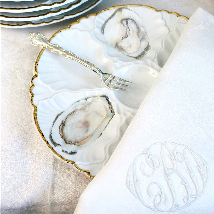 Collectiable antique white and gold oyster plates with sterling fork monogrammed napkin and oysters