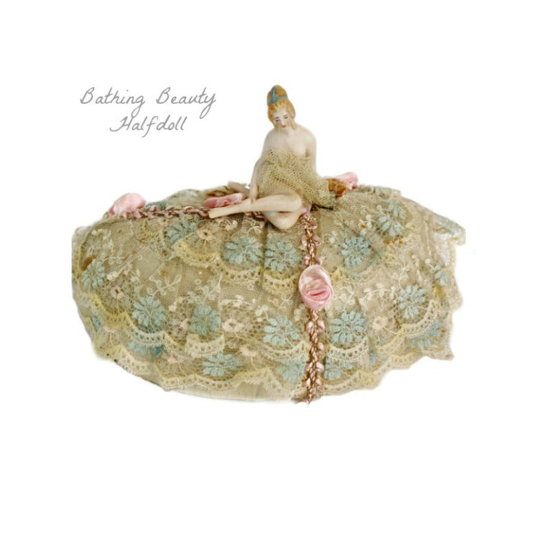 Antique bathing beauty half doll pincushion with French lace and pink ribbon, featuring a painted face and a skimpy net skirt.
