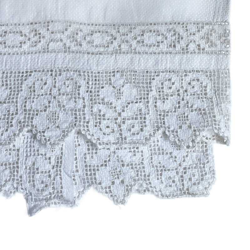 Close-up of a white lace fabric with intricate patterns on a white background