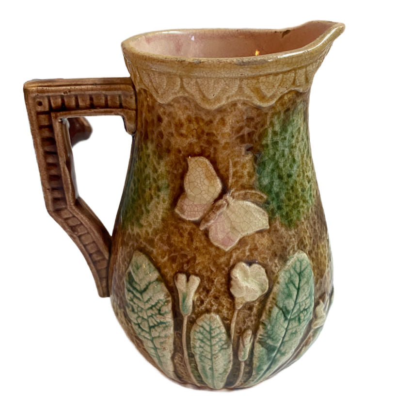 Antique French Majolica Pitcher with violets and butterflies, pink interior and aged patina—romantic 19th-century French country charm.