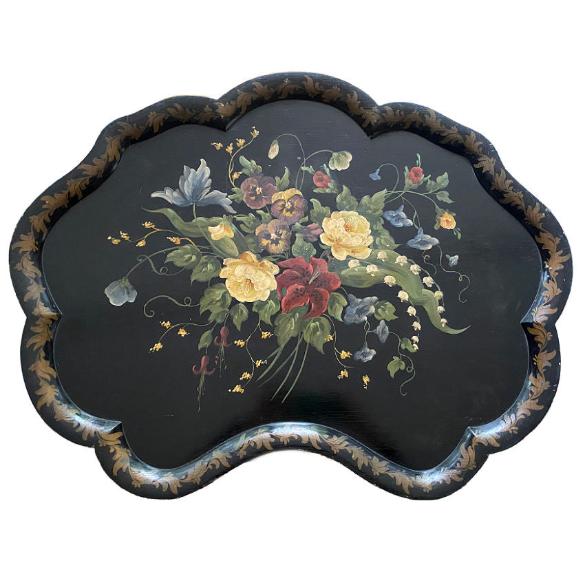 Antique scalloped black tole tray with hand painted floral designs including pansies and lily of the valley, with gold accents around the perimeter.