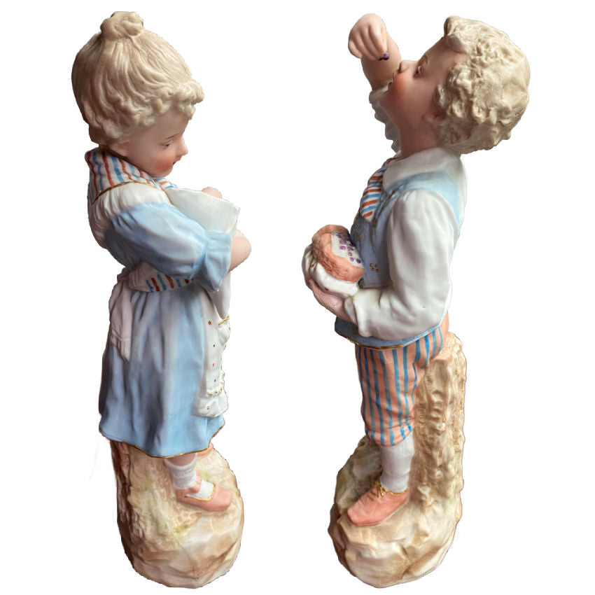 Rare matched pair of antique Gebrüder Heubach bisque figurines of a girl and boy enjoying sweets. Exquisite German craftsmanship, circa 1900.