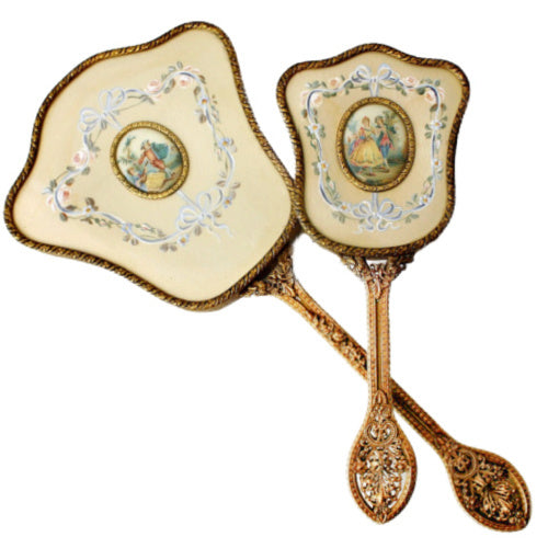 Exquisite hand-painted vanity mirror and brush set with gilt filigree and romantic courting scenes. A rare and elegant treasure for the antique dressing table.