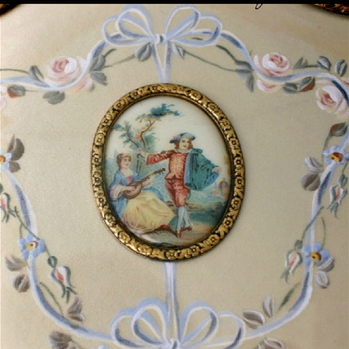 Exquisite hand-painted vanity mirror and brush set with gilt filigree and romantic courting scenes. A rare and elegant treasure for the antique dressing table.