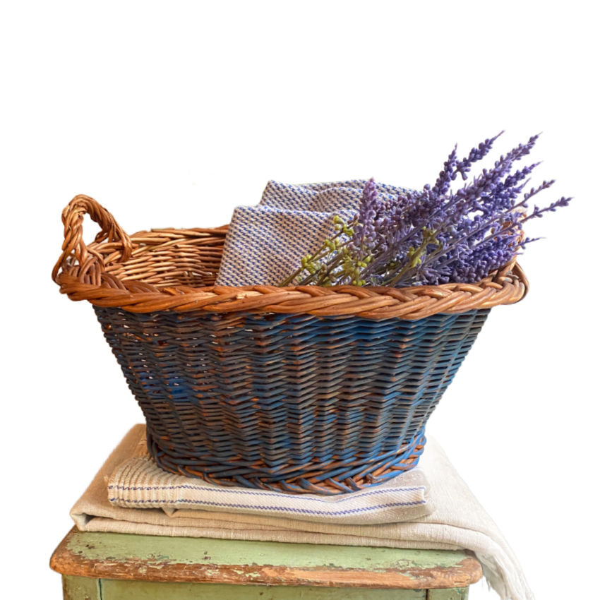 Vintage Dutch faded Delft painted wicker basket styled with antique linens and lavender on an antique chair