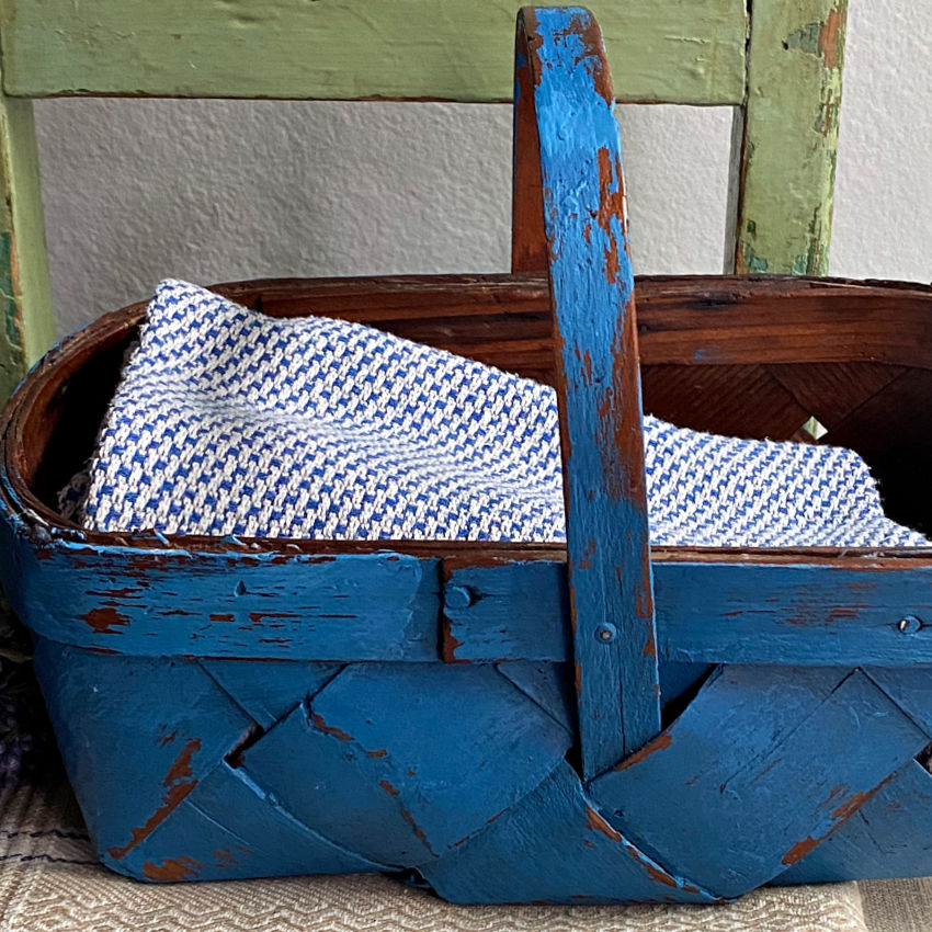 Close-up of the wide splint weave and distressed blue finish on a vintage Normandy basket.
