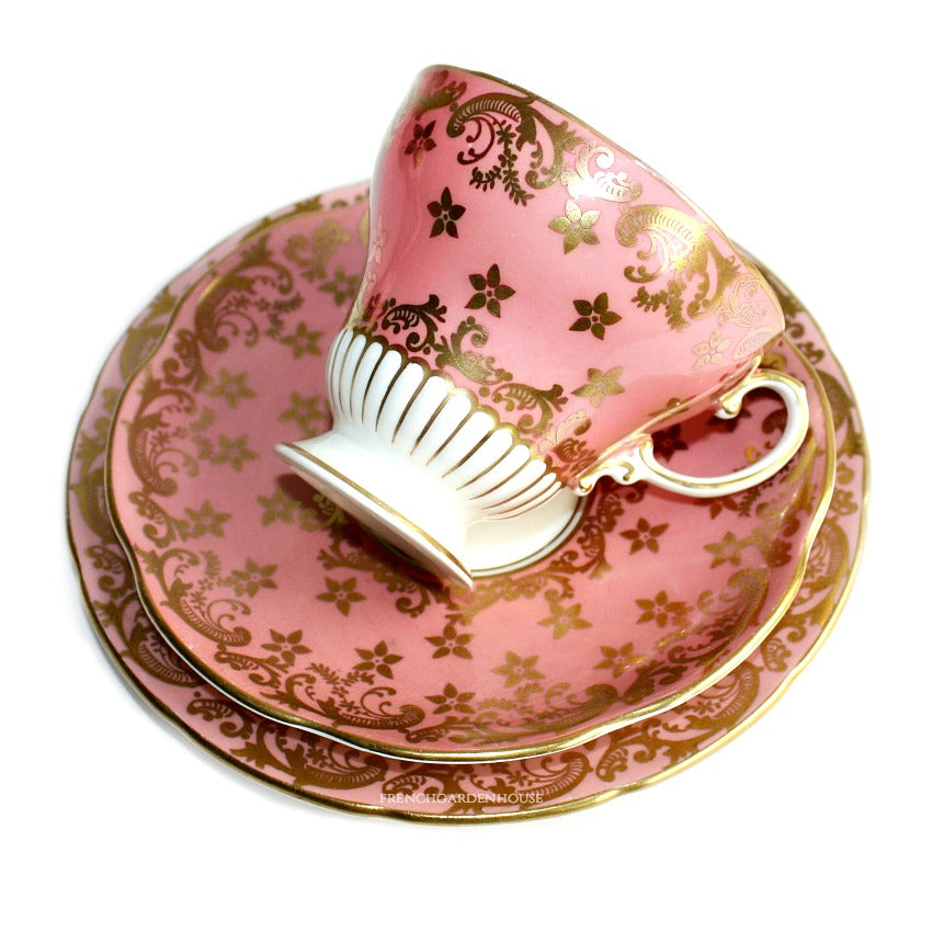 A vintage pink apricot tea cup with a floral pattern and gold accents, accompanied by a matching dessert plate with a similar design.