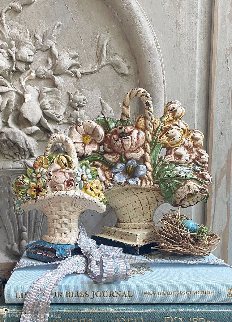 A collection of antique floral,doorstops stacked on a group of books tied with ribbon.