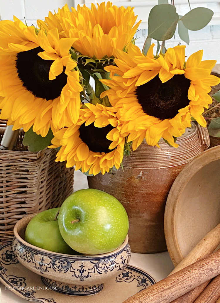 Golden sunflowers displayed in an antique French stoneware pitcher with a rustic French Country feeling