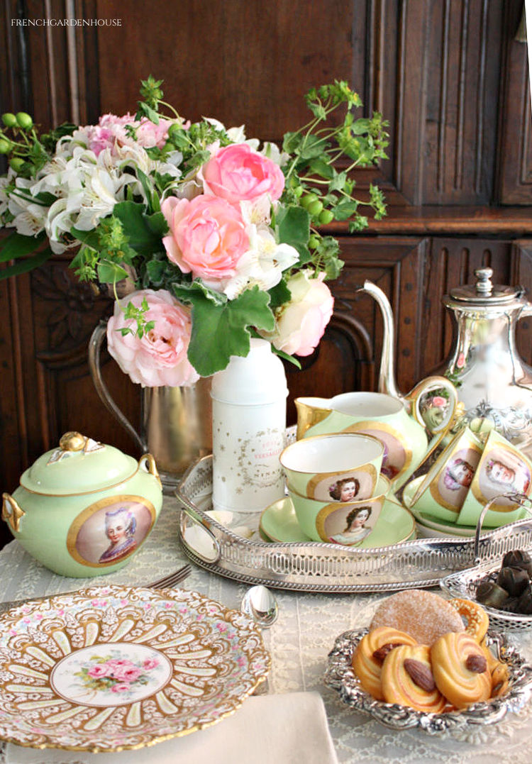 Antique French Sevres Vieux Paris porcelain tea cups and sugar and creamer set, on a lace covered tea table with cookies and a vase of pink roses  