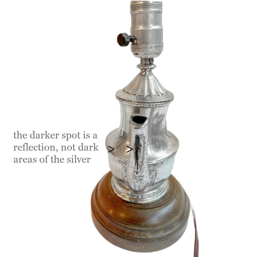 Close detail of silver spout surface showing natural wear and time-softened finish