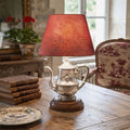 1940s hotel silver teapot lamp styled in French country living room on table with red toile chair and books