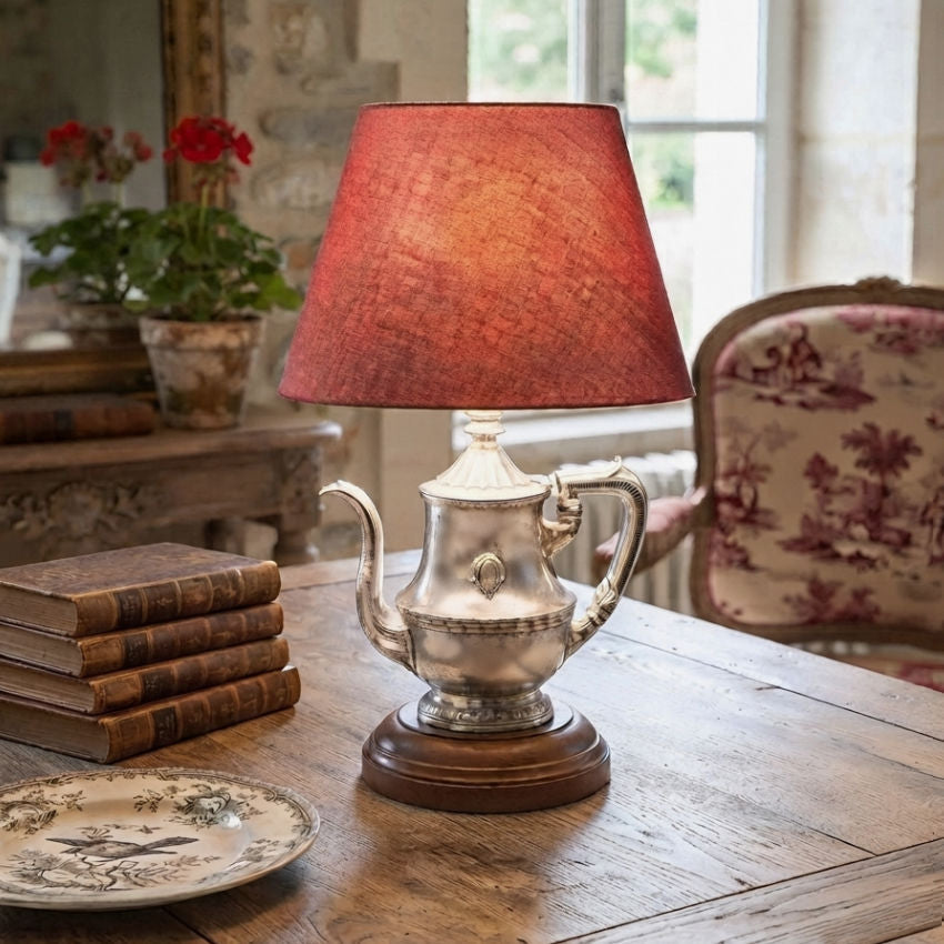 1940s hotel silver teapot lamp styled in French country living room on table with red toile chair and books