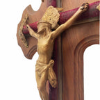 Profile view of bronze Corpus on antique French crucifix mounted on red velvet cross with decorative cross caps