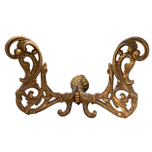 Ornate 19th-century French gilt cast iron double wall hook with Rococo foliate scroll details and authentic gold patina.
