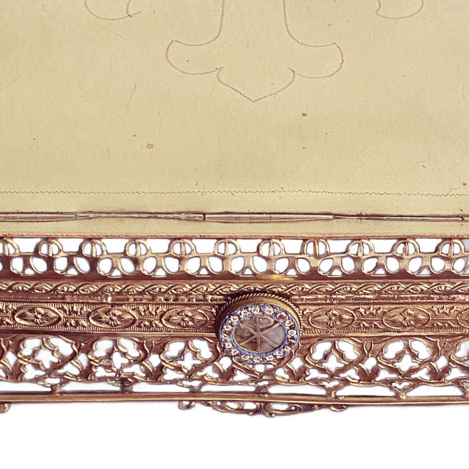 Close-up of the engraved cross and ornate floral brasswork on an antique French Bible stand
