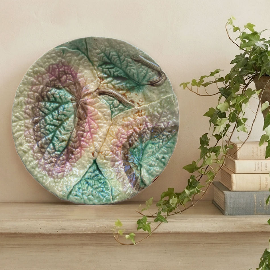 19th century English Majolica begonia plate styled on a wood shelf next to a stack of books an an ivy plant