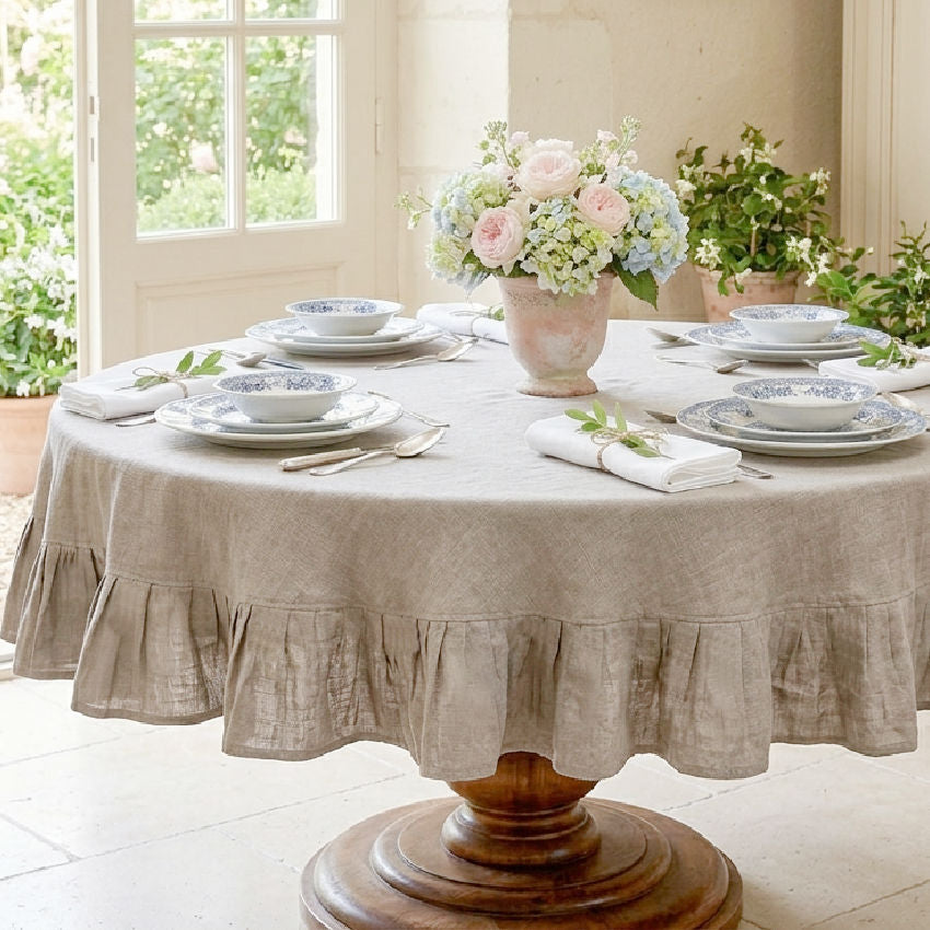 Elegant round linen table set in warm neutral flax tones for gathering