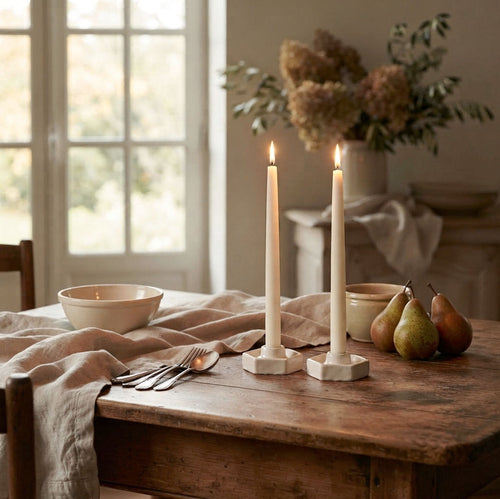 Abeille white pottery taper candle holders with candles on table with linen and pears