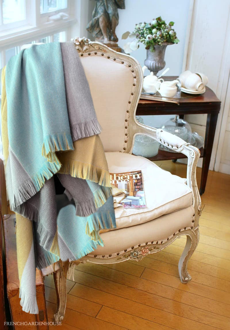Reversible alpaca blanket draped over French country chair in soft green and lavender purple  tones