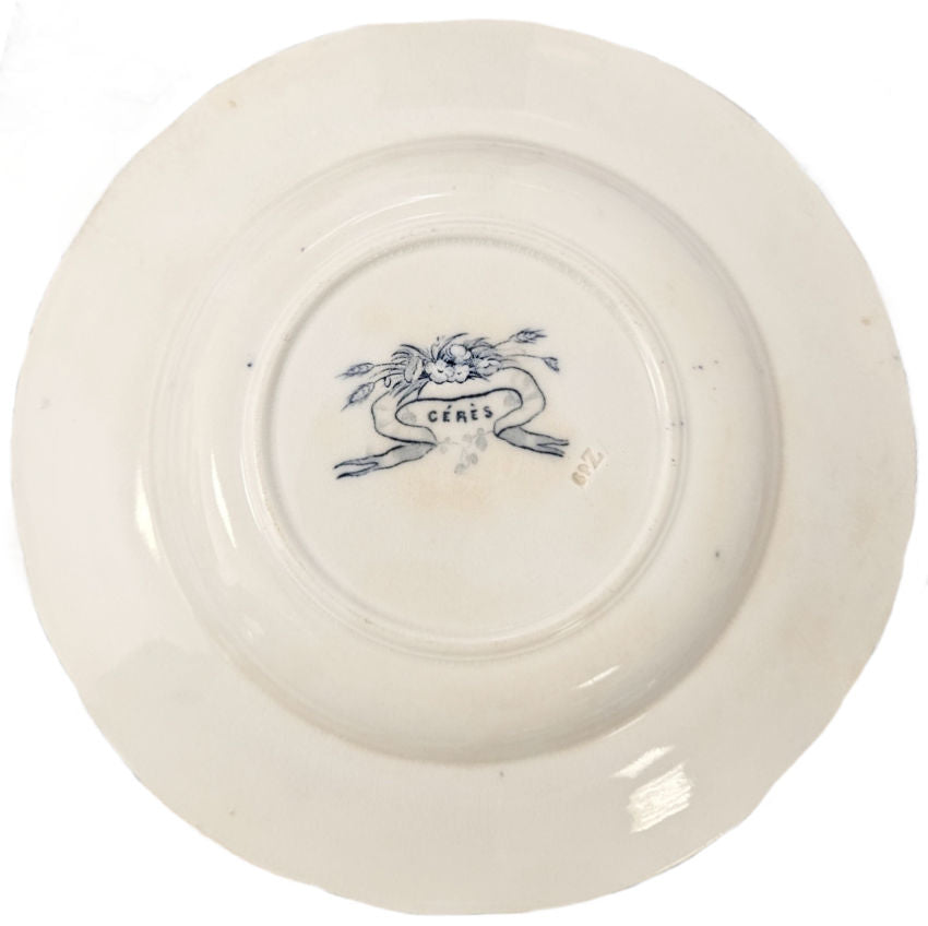 A detailed view of an 1870s French Sarreguemines Cérès pattern deep plate, showcasing intricate blue and white floral transferware details. showing back stamp