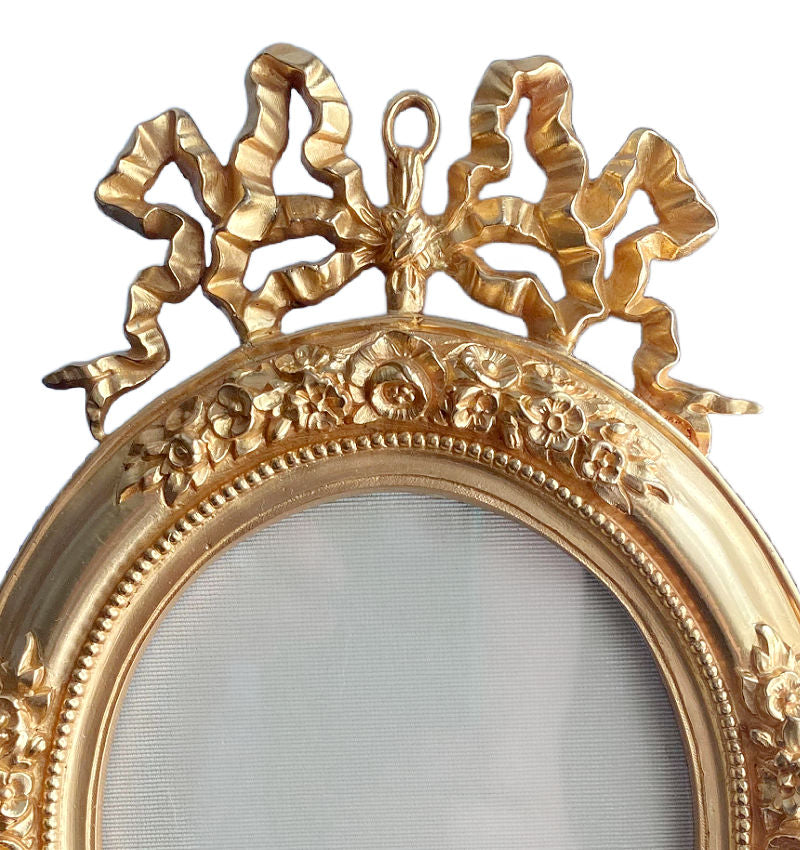 close up of ribbon bow crest on antique bronze doré frame