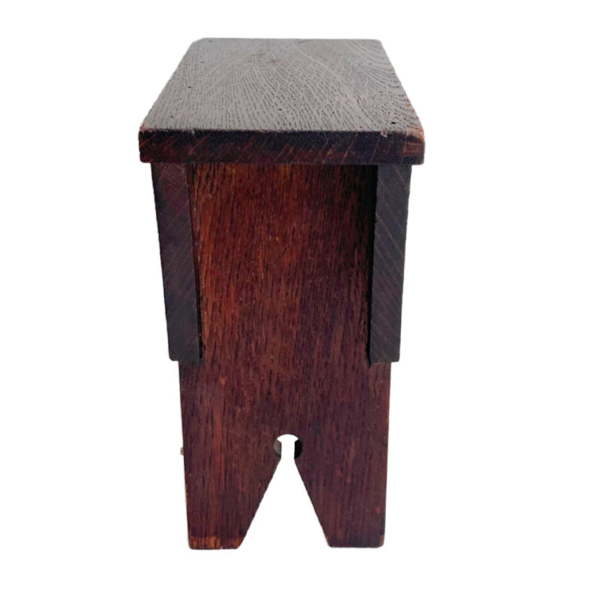 Antique oak money box in the shape of a country stool, stained in deep espresso brown color, viewed from a slightly elevated angle against a white background.