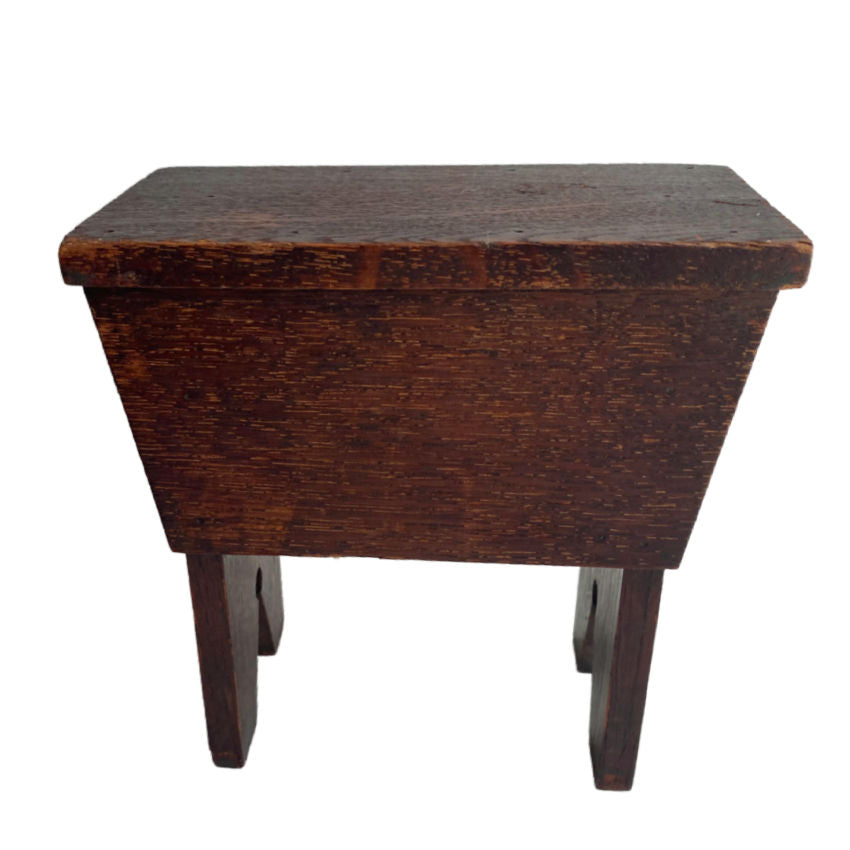 Antique oak money box in the shape of a country stool, stained in deep espresso brown color, viewed from a slightly elevated angle against a white background.