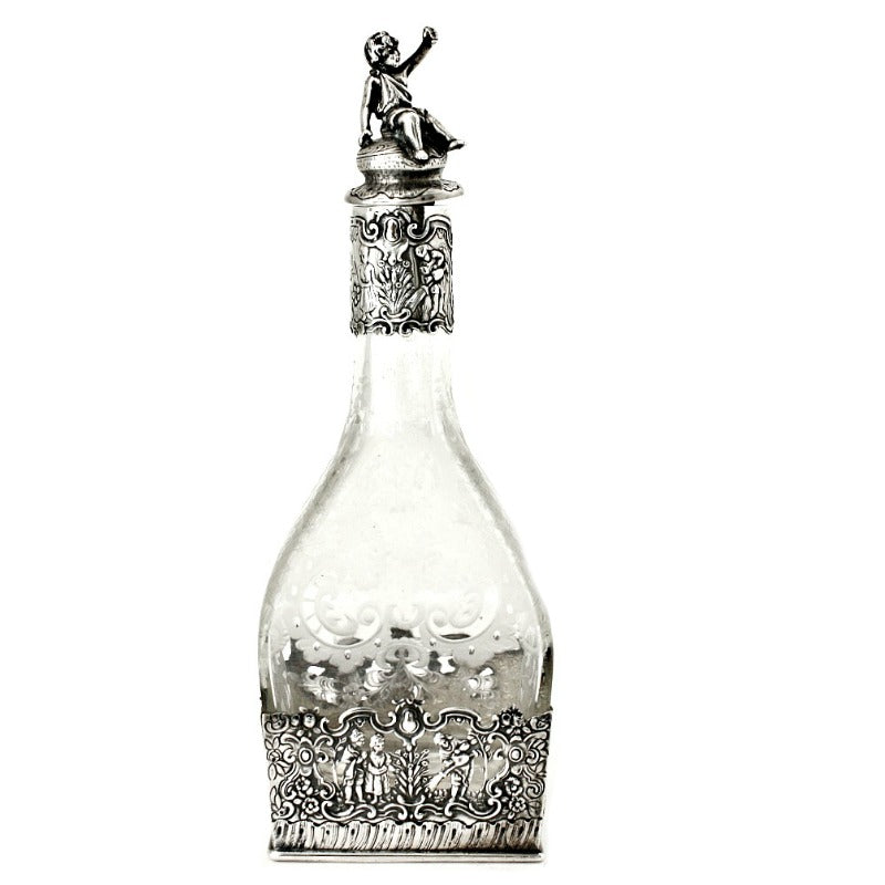 Antique Sterling Silver Repousse Cherub Overlay Etched Crystal Decanter with a floral etching and a figurine of a cherub on the top, featuring a lush garden scene.