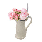 Antique Parian porcelain syrup pitcher with a wheat design, filled with pink roses, against a white background