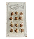 A collection of twelve antique French gold and cream cufflinks and collar buttons displayed on an original card with 'Nouveaute de Paris' printed on it.