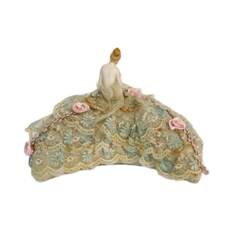 Antique bathing beauty half doll pincushion with French lace and pink ribbon, featuring a painted face and a skimpy net skirt.