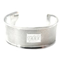 Antique sterling silver cuff bracelet with monogram engraving, displayed against a white background.