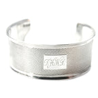 Antique sterling silver cuff bracelet with monogram engraving, displayed against a white background.