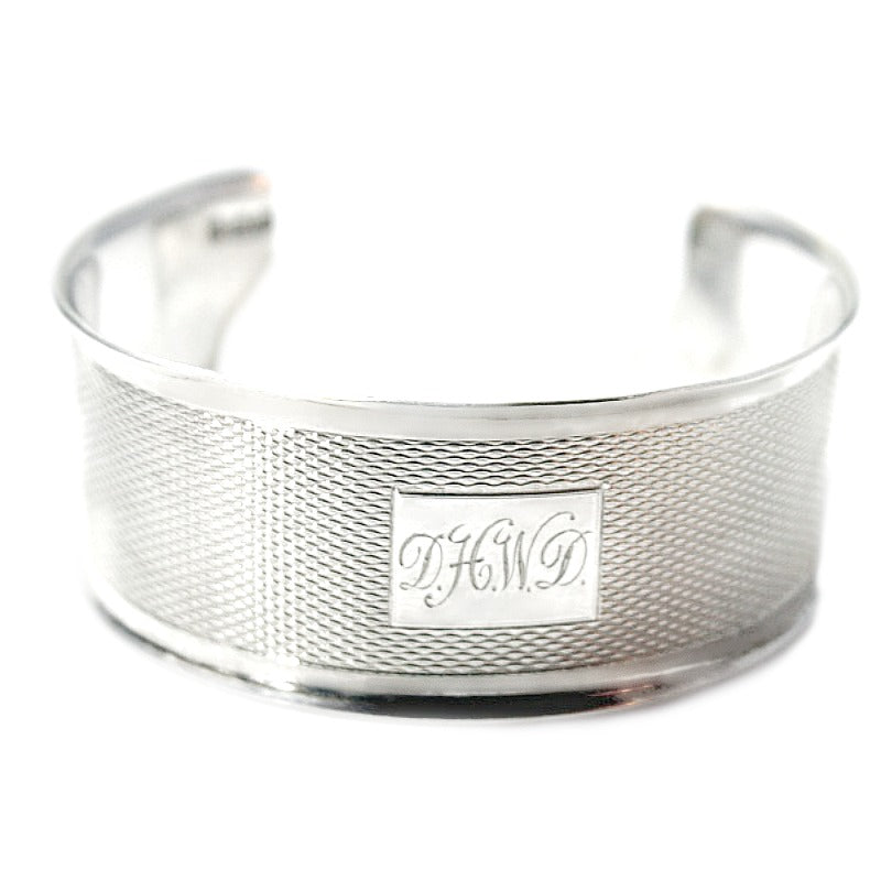 Antique sterling silver cuff bracelet with monogram engraving, displayed against a white background.