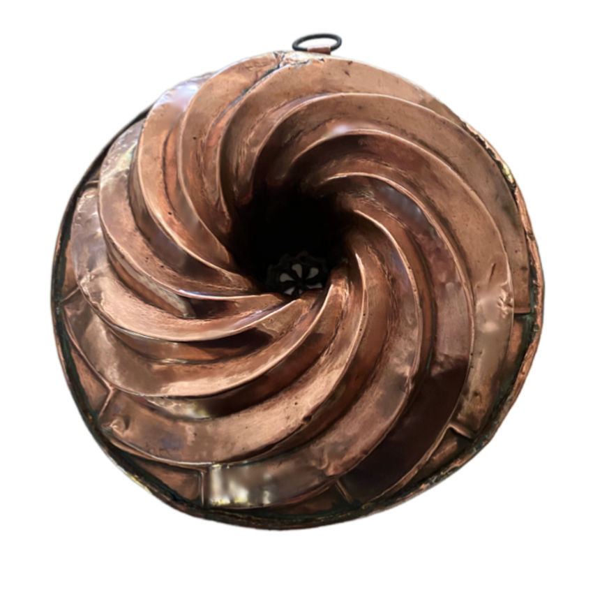 Antique French copper bundt mold with sculptural spiral fluting and rich aged patina. A striking European heirloom for kitchen or wall display.