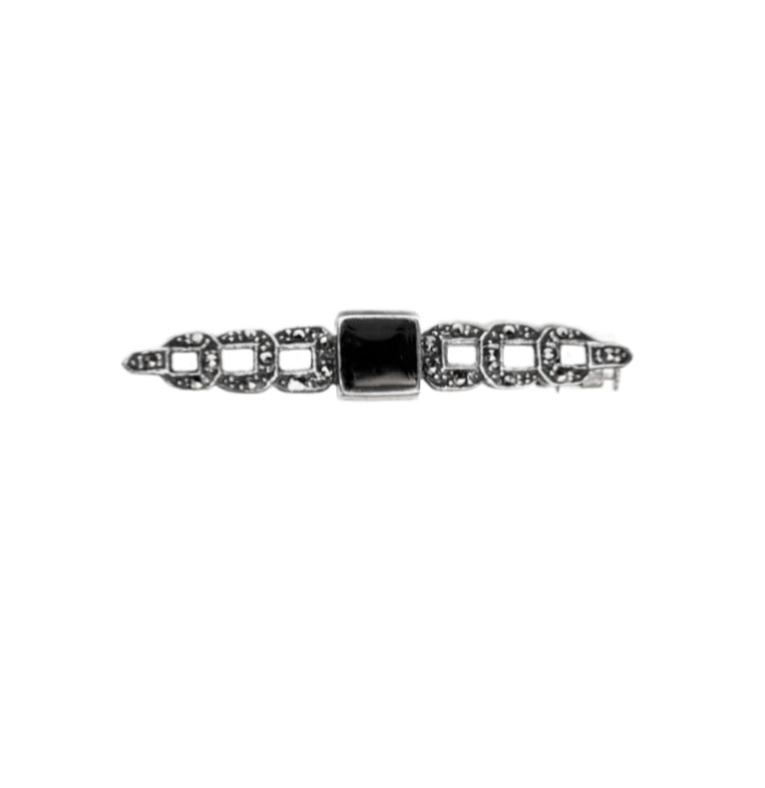 A sterling silver bar pin with a central black onyx stone and small marcasite decorations.