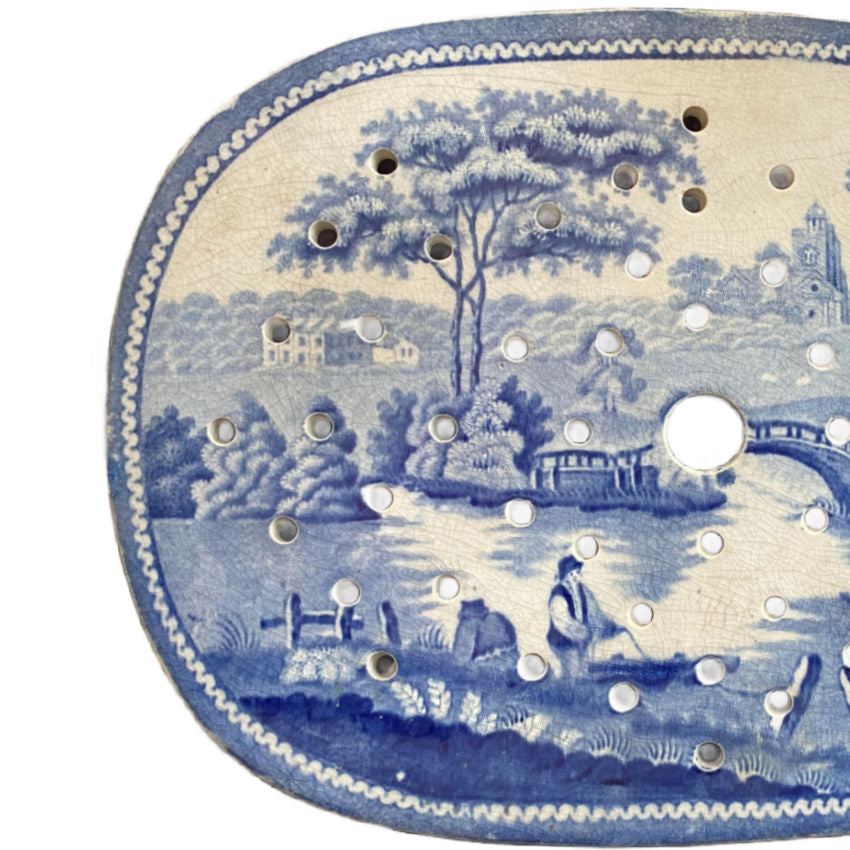 Blue and white transferware meat drainer, English ironstone, top-down view showing pattern and left edge.