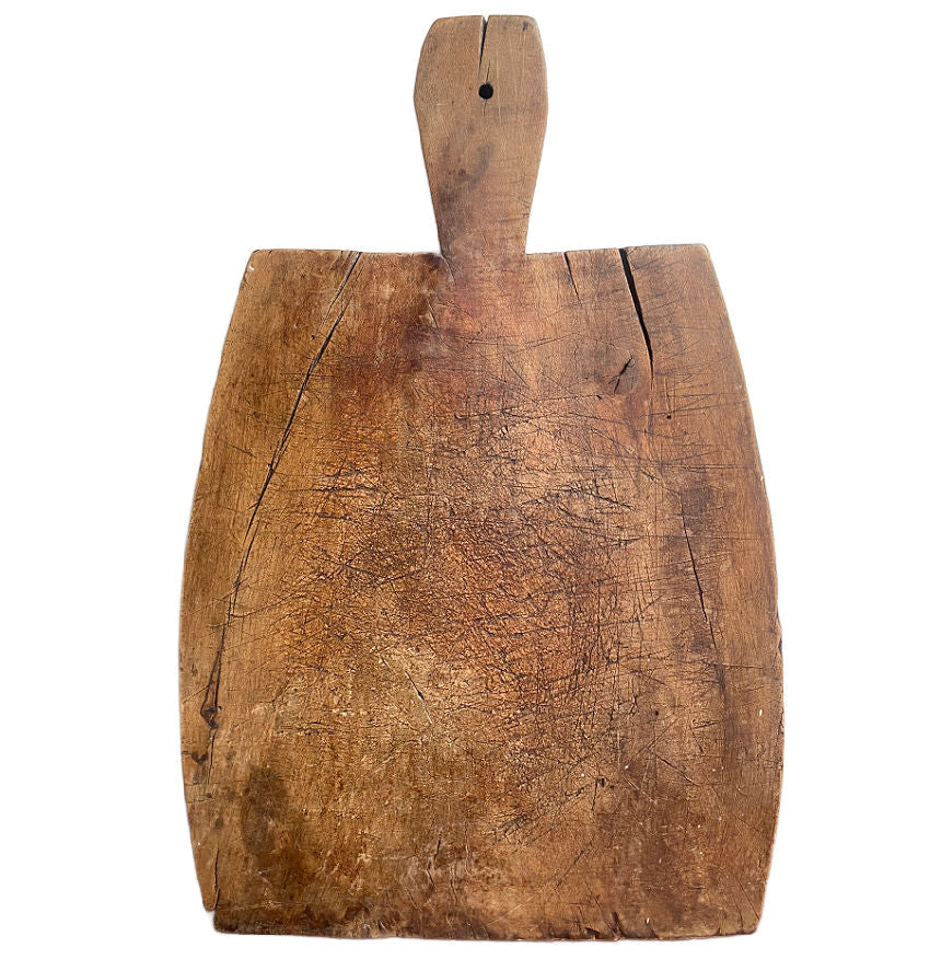 Antique French hand-carved wooden cutting board with a dark patina and a short handle.