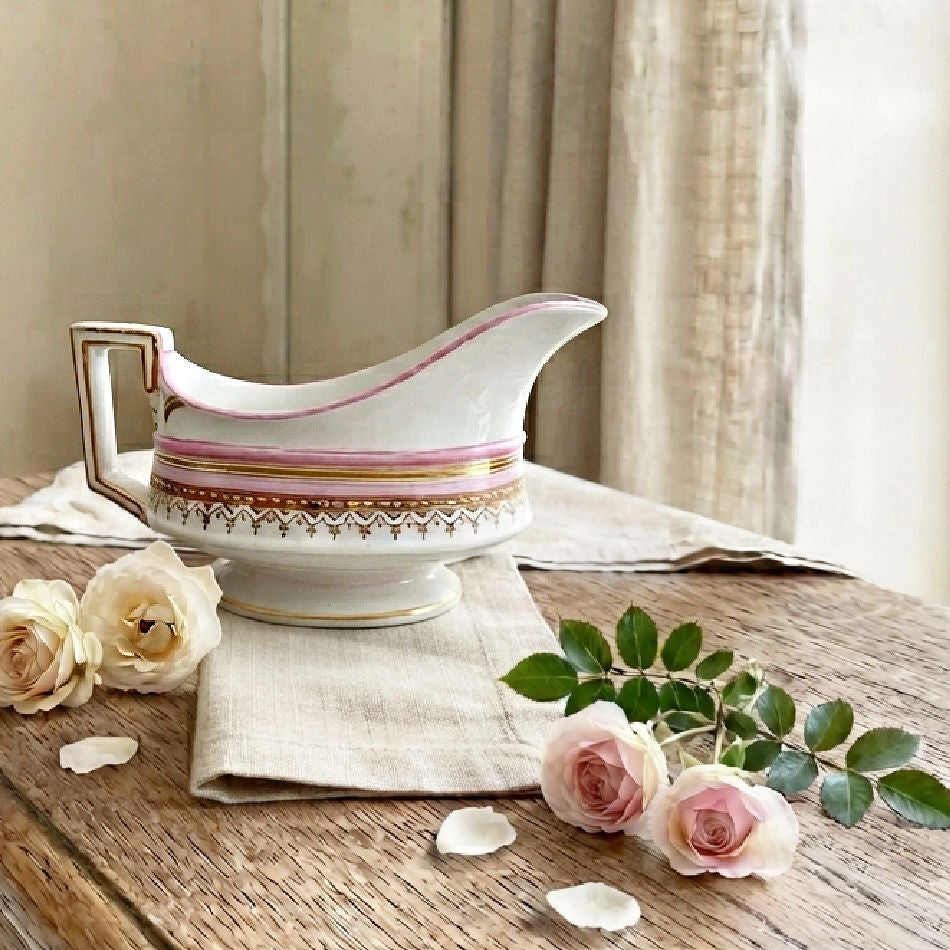 Antique French tableware styled in an elegant french country dining room with roses and linens on a wood table