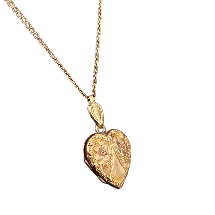 Antique heart locket with two raised forget-me-not flowers close up