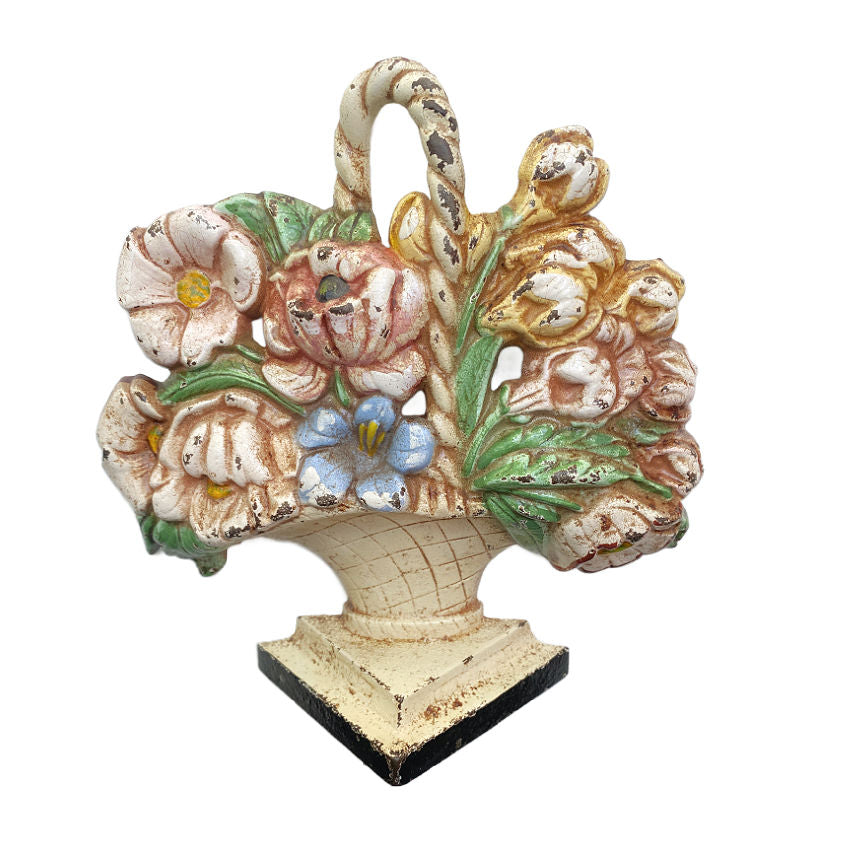 Antique Hubley cast-iron floral basket doorstop with pastel colored flowers and a cream basket with a handle, on a triangular plinth base.