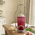 Antique James W. Tufts silver plate cranberry glass pickle castor styled on a French room table with pink roses, chandelier light, and timeless elegance
