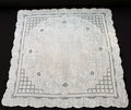 An antique white linen handkerchief with embroidered floral and geometric designs, scalloped edges, and a small border.