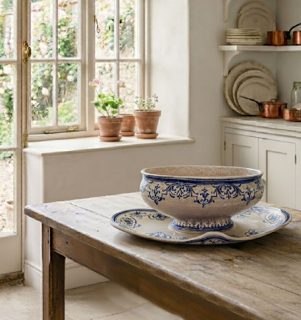 Antique Moustiers faience sauce boat with in a country kitchen with light streaming in, on an antique French table