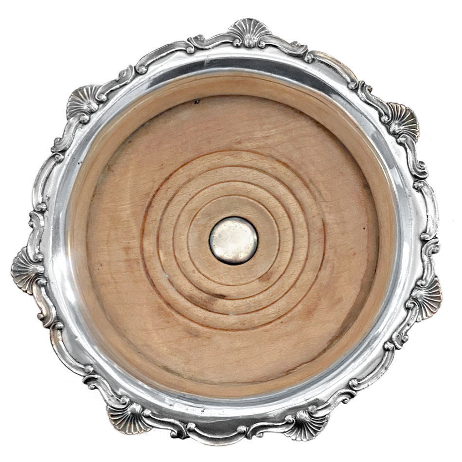 Close-up of raised shell detail on antique silver-plated champagne coaster silver button light wood
