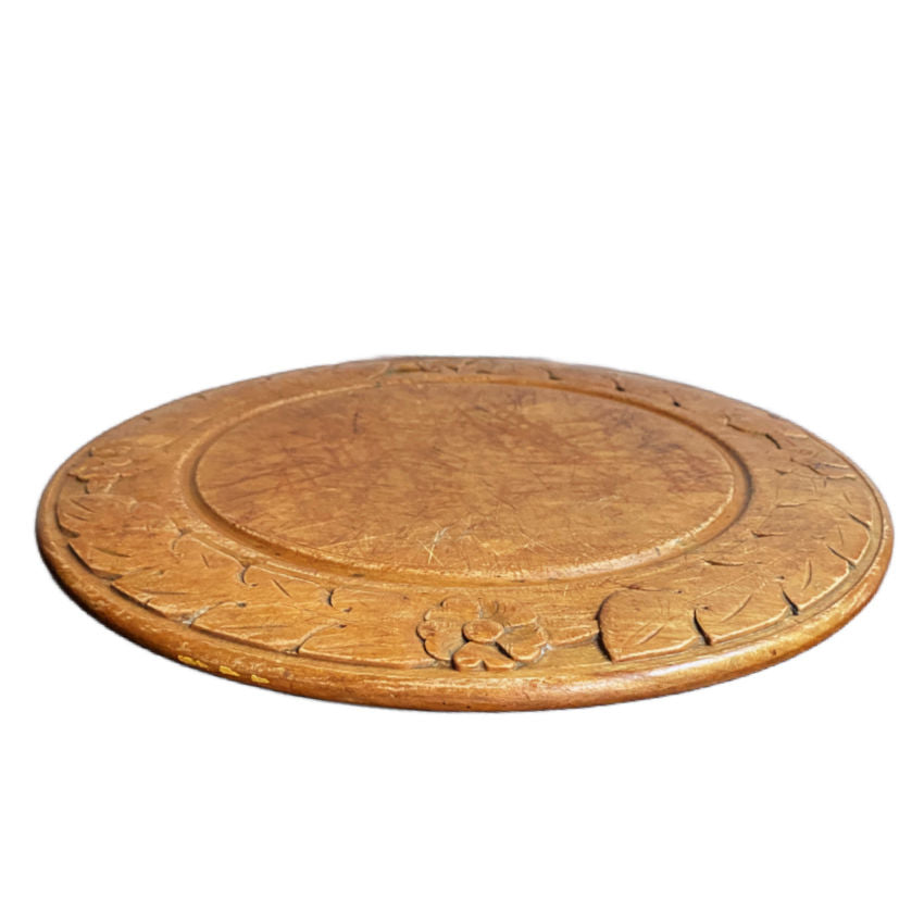 close detail of wild rose carved border and side on round wooden board