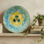 Antique 19th century majolica bowl with leaf and vine decoration on shelf with books and ivy